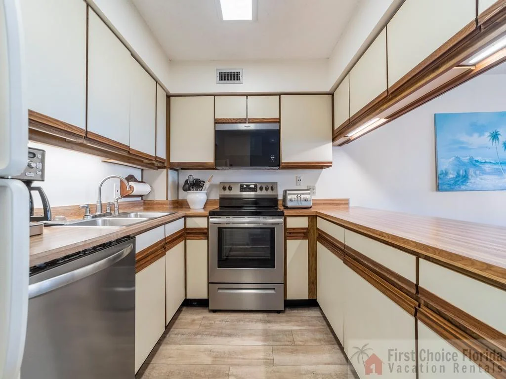 U-shaped kitchen with wood-trimmed cabinets, stainless steel appliances, and under-cabinet lighting.