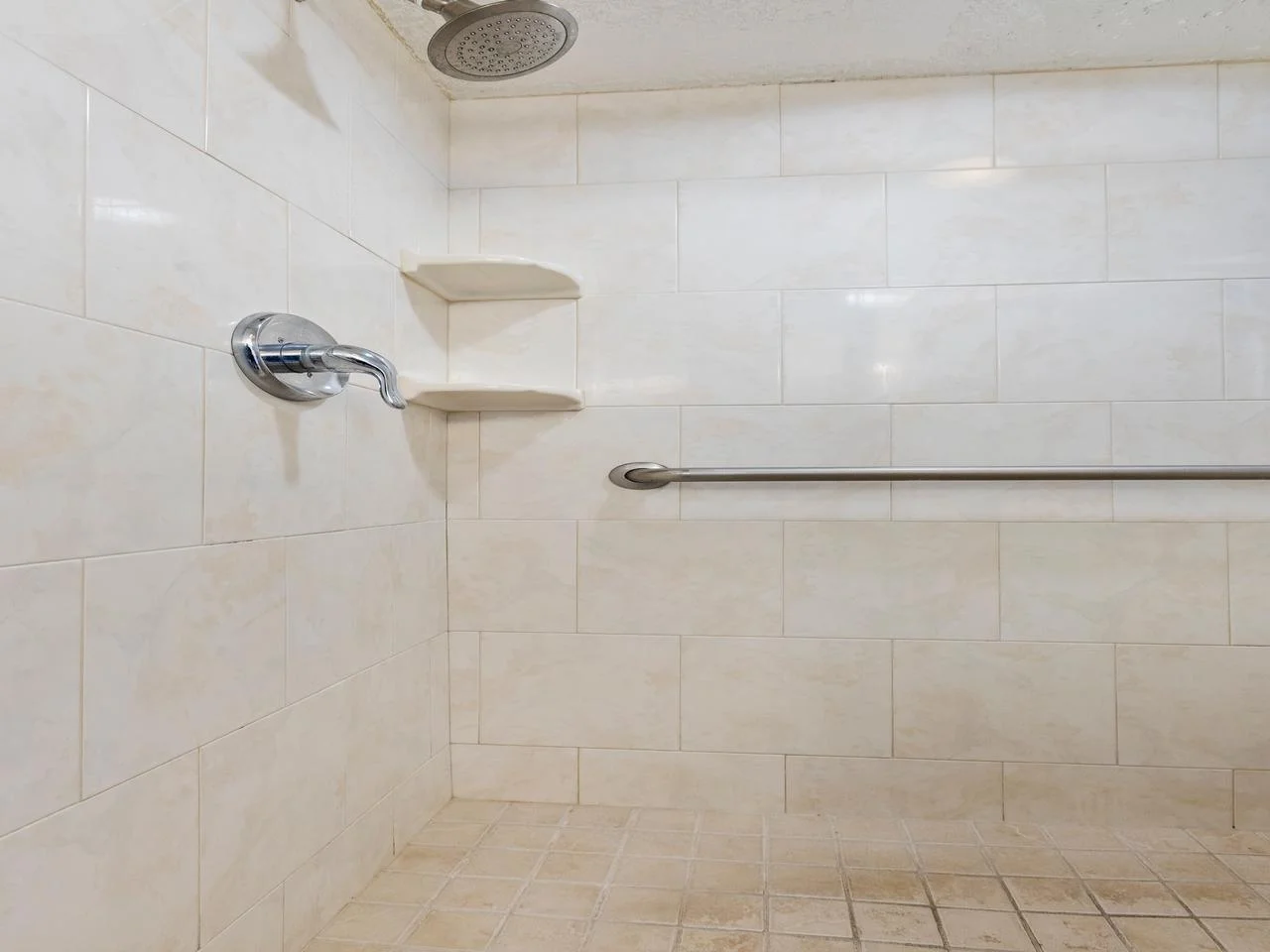 Spacious walk-in shower with modern fixtures and built-in shelves
