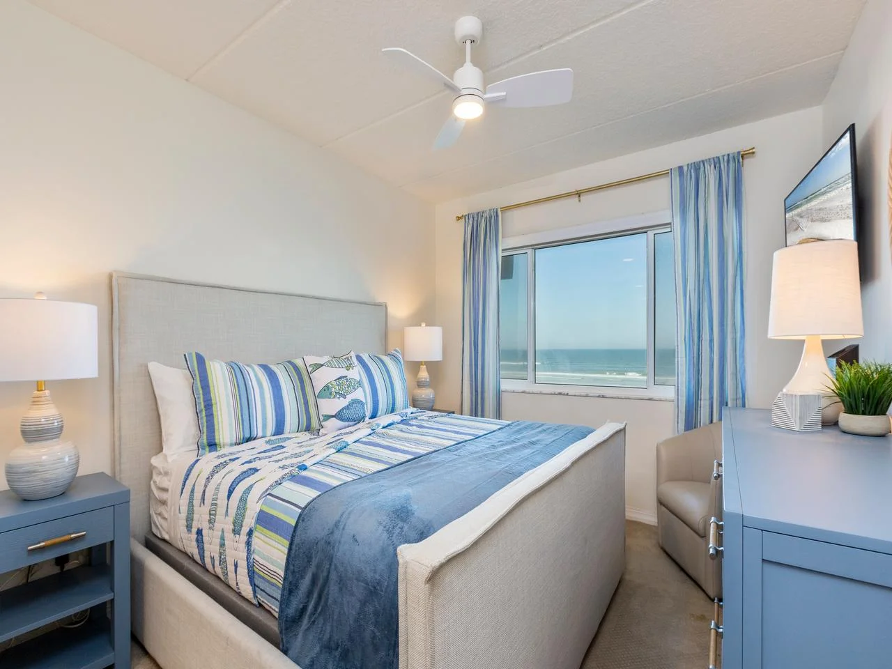 Cozy primary king bedroom with serene ocean views and calming blue accents!