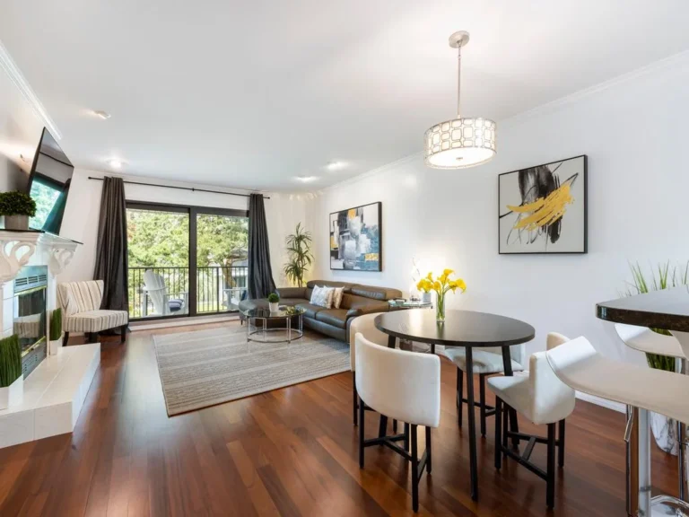 Dark wood floors extend through the living and dining area, featuring a leather sofa and round table under a geometric pendant.