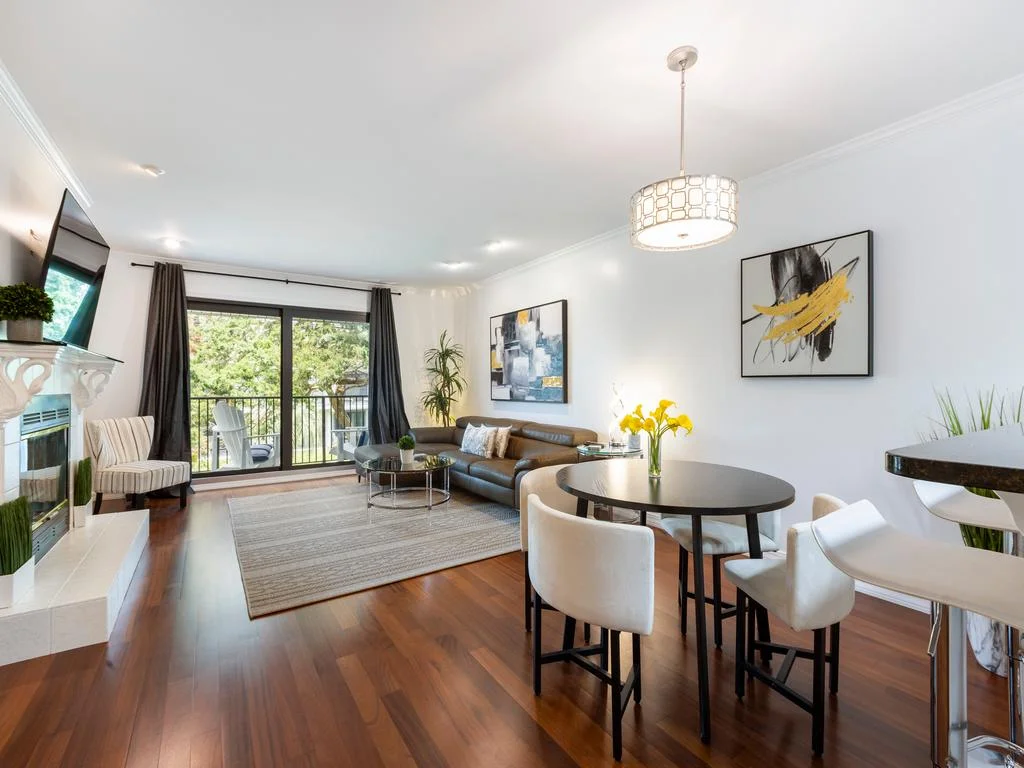 Dark wood floors extend through the living and dining area, featuring a leather sofa and round table under a geometric pendant.