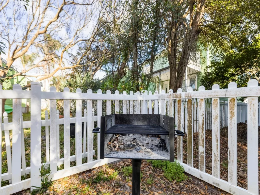 Cozy outdoor park grill surrounded by charming white picket fence!