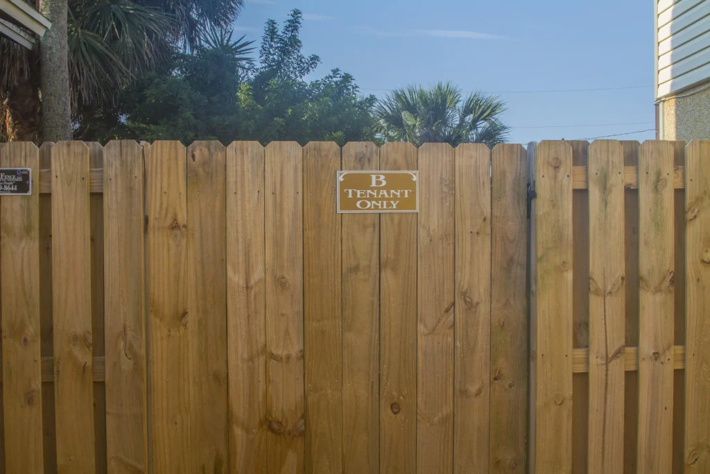 Vertical wood fence panels with a small sign indicating exclusive access for "B Tenant Only" under a clear blue sky.