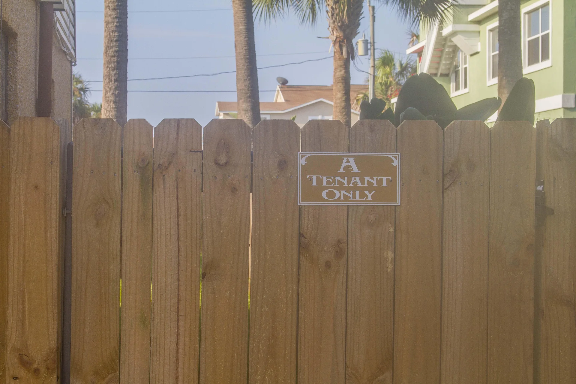 Wooden privacy fence with natural grain and a small sign reading "A Tenant Only" blocks the view beyond.