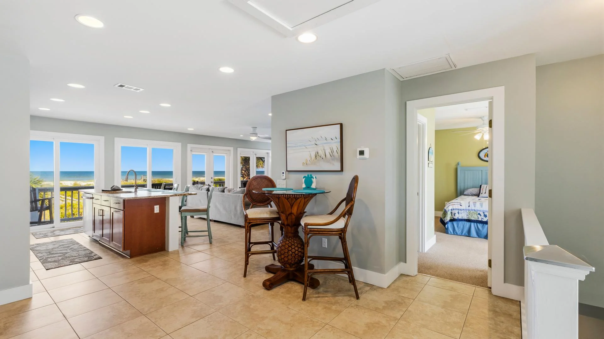 Tiled floor leads to a tropical-style glass-top table with two wicker chairs in the dining nook.
