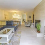 Living room with gray leather sectional, white wood coffee table, patterned armchair, and tiled fireplace wall.