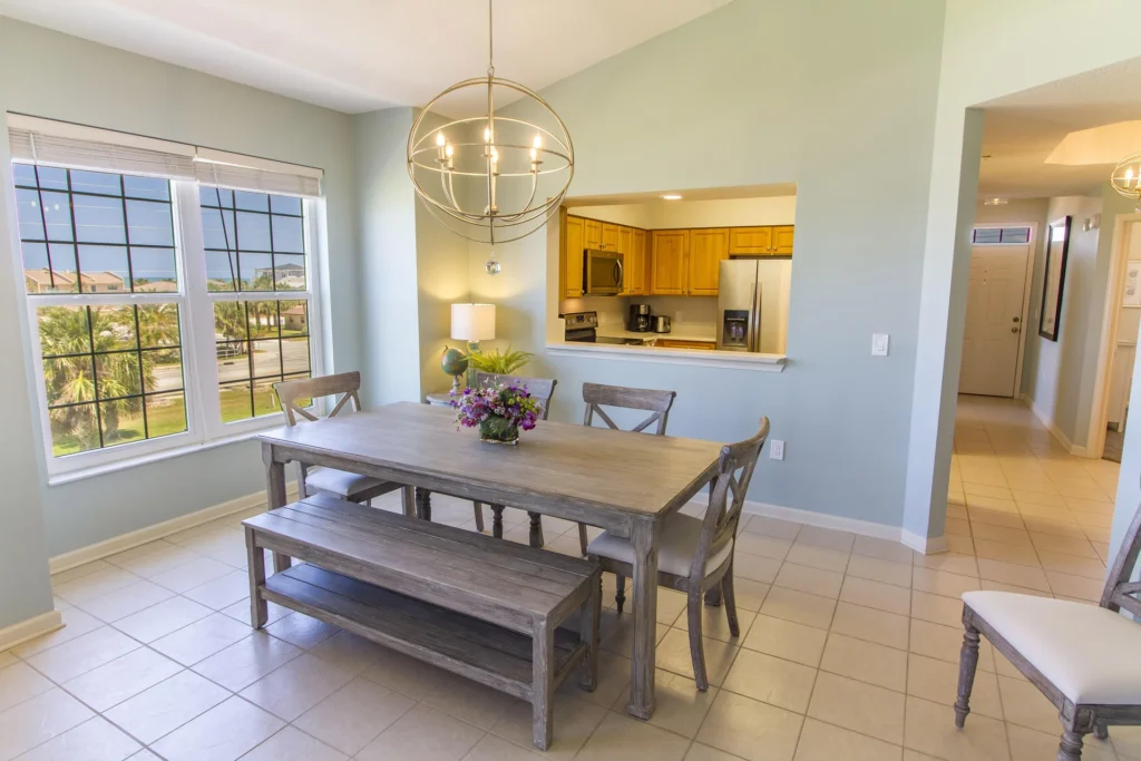 Dining area with weathered wood table, bench seating, cross-back chairs, and spherical metal chandelier.