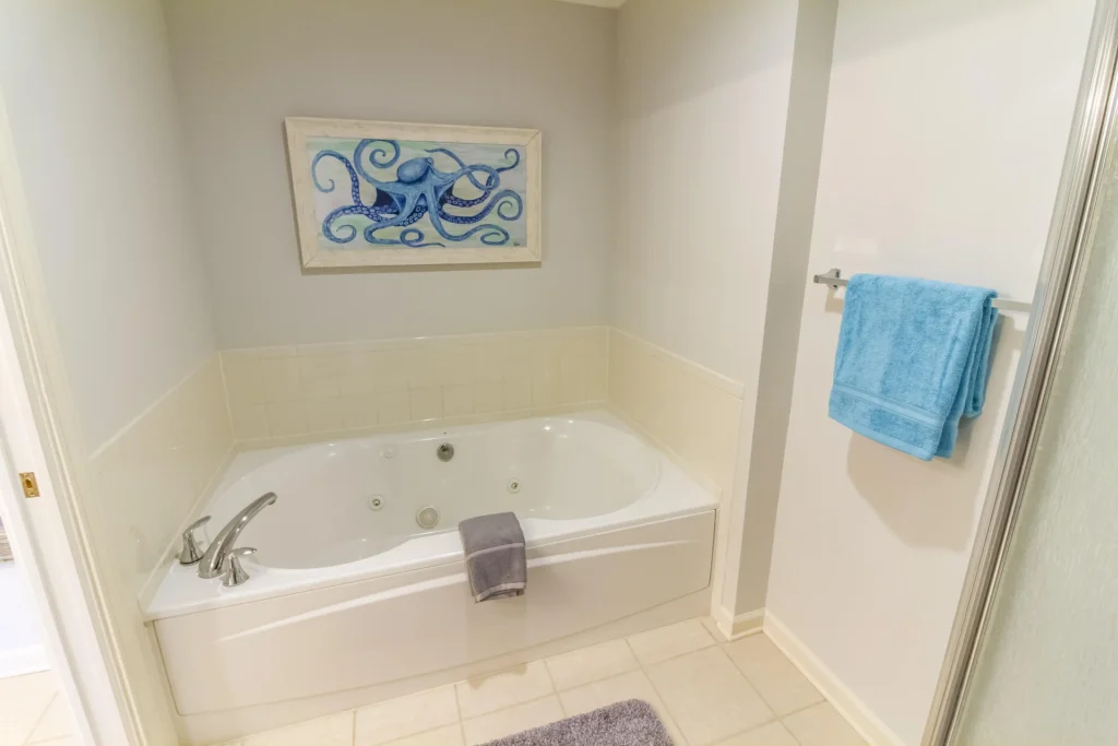 Whirlpool soaking tub with brushed nickel fixtures, cream tile surround, and octopus artwork above.