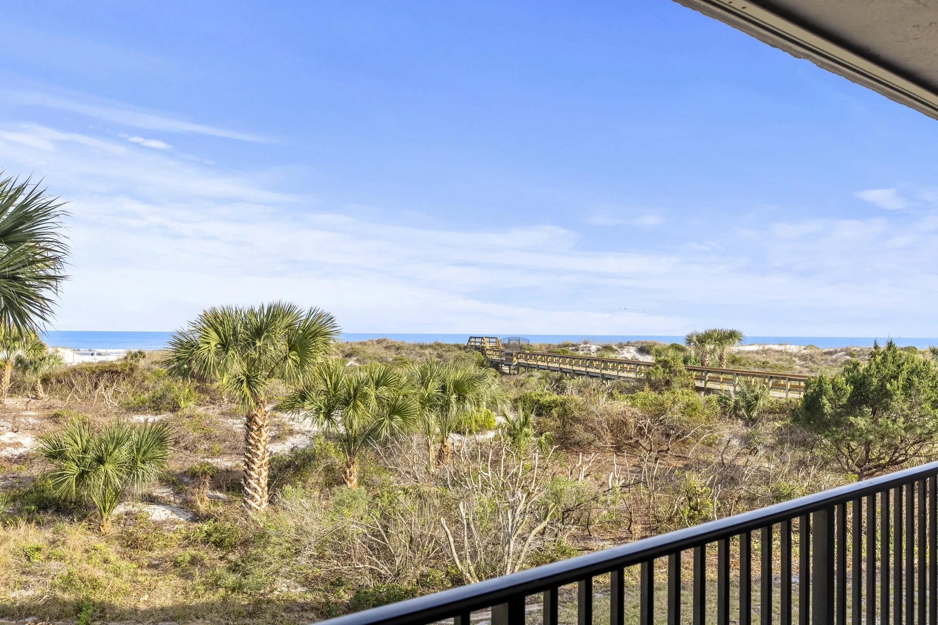 Ocean-view balcony overlooking lush coastal greenery and blue skies