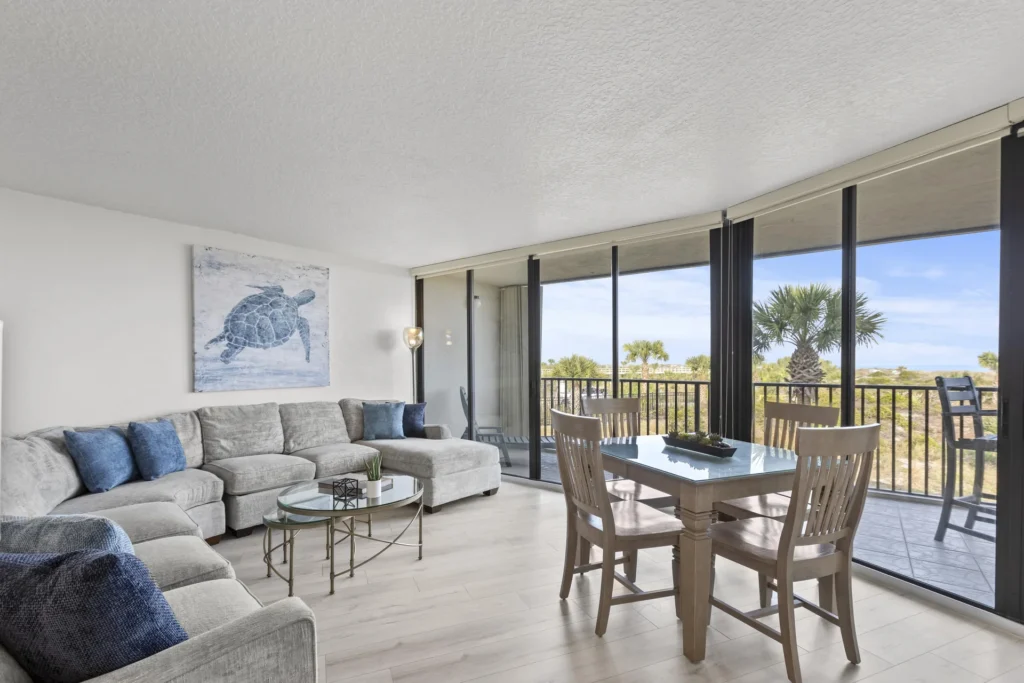 Sunlit living and dining area with panoramic balcony to ocean views