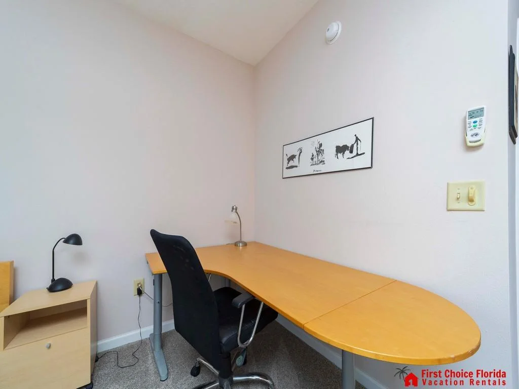 An extended honey wood desk with rounded edges sits beneath minimalist black-and-white artwork.