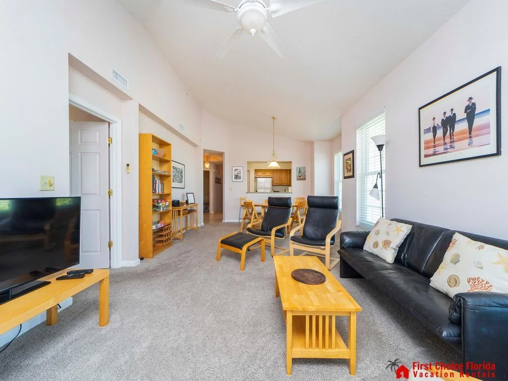 Black leather sofa and chairs flank a honey wood coffee table on soft gray carpet in the living room.