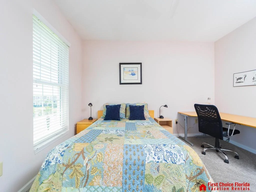 Patchwork quilt covers the bed flanked by light wood nightstands and twin black reading lamps.