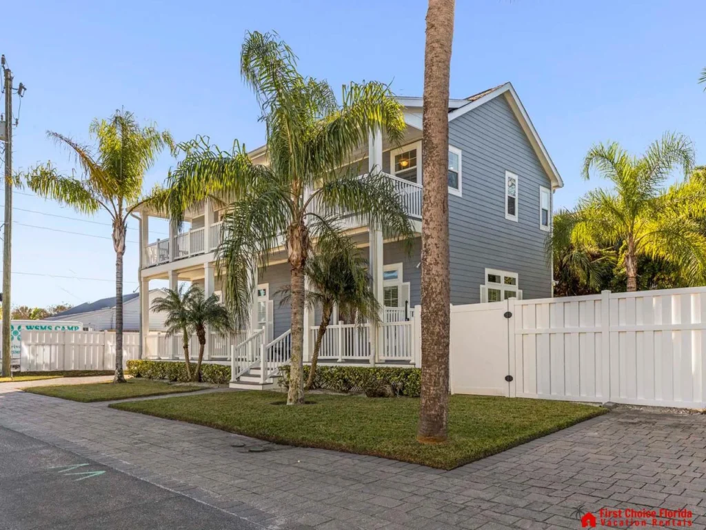 Charming exterior with lush palm trees and private fence