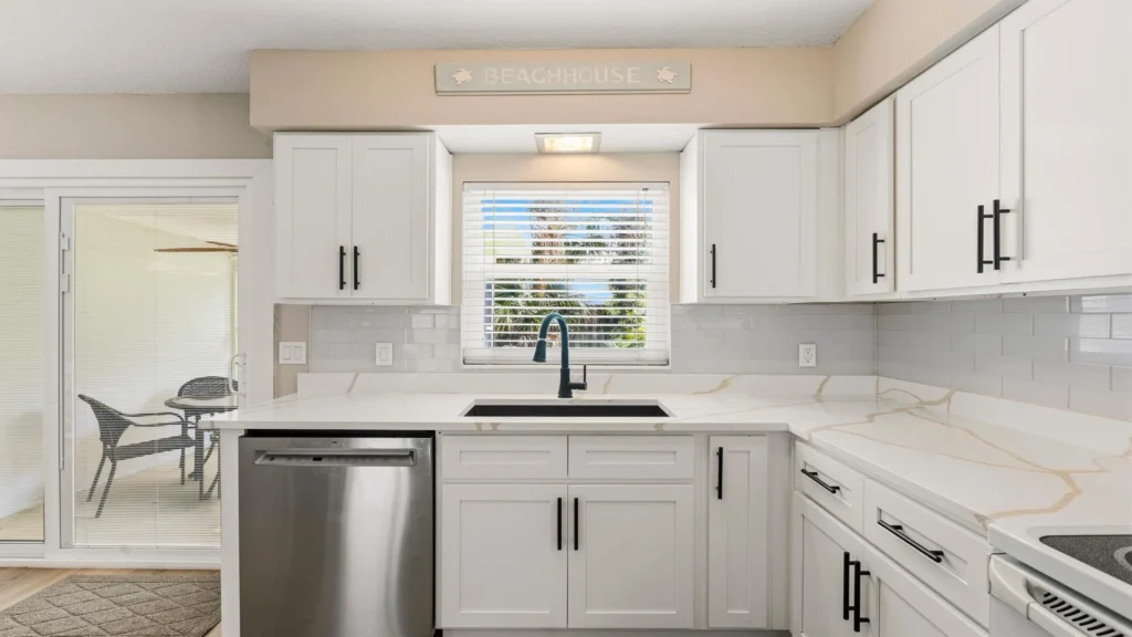 Kitchen features marble-look countertops, white subway tile backsplash, black faucet, and sliding door to patio.