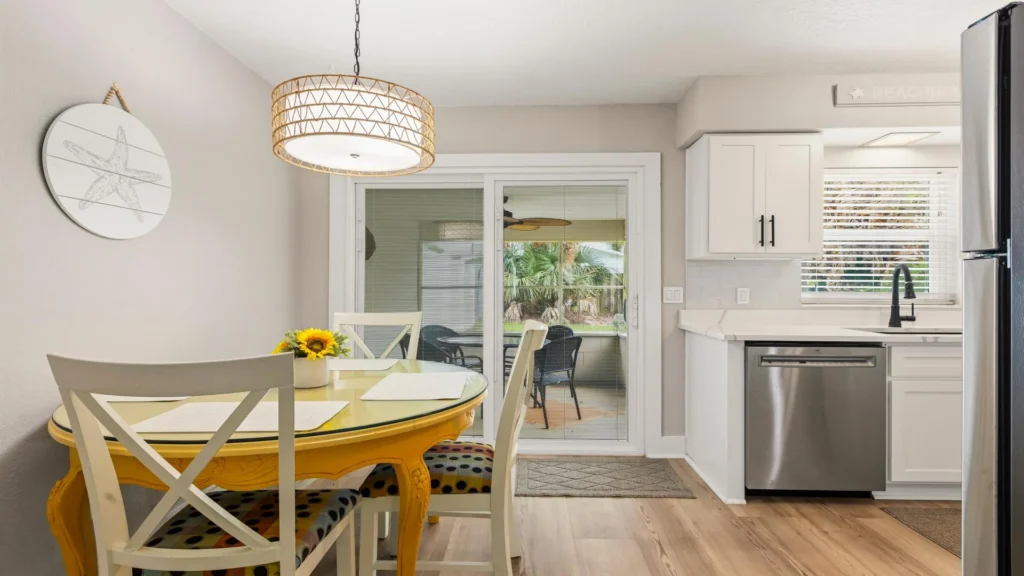 Dining area with glass-top yellow table, white chairs with polka dot cushions, and sliding glass door to patio.
