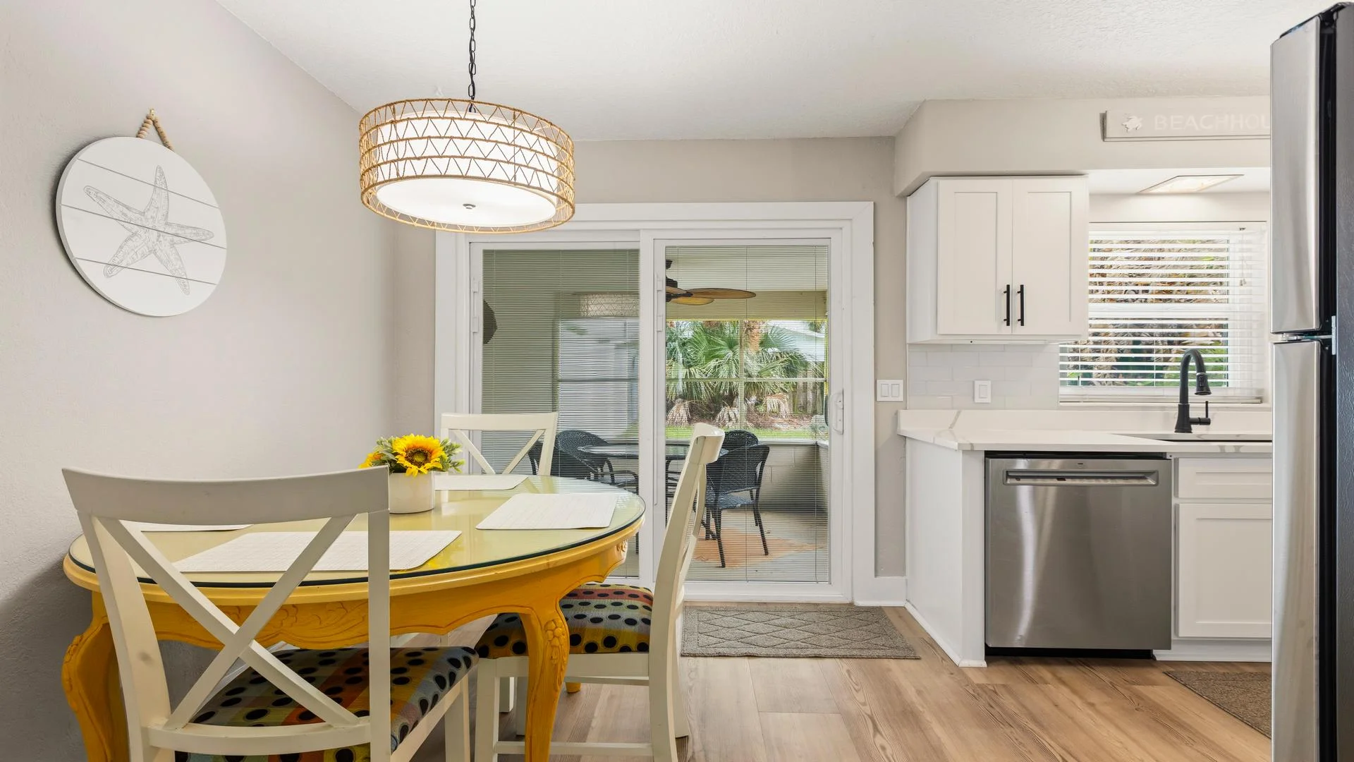 Dining area with glass-top yellow table, white chairs with polka dot cushions, and sliding glass door to patio.