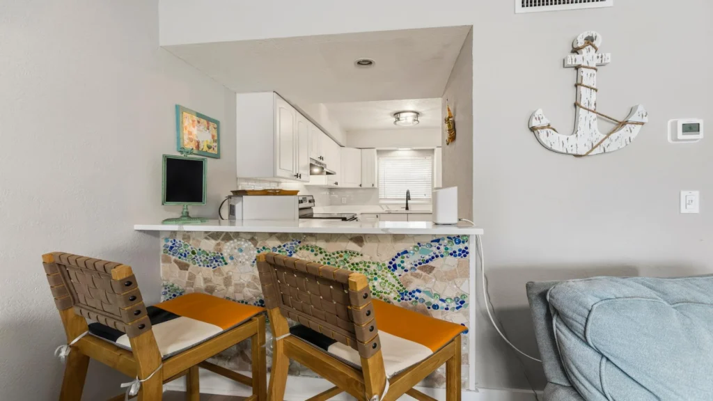 Kitchen pass-through bar decorated with mosaic tile and paired with woven leather strap wooden stools.