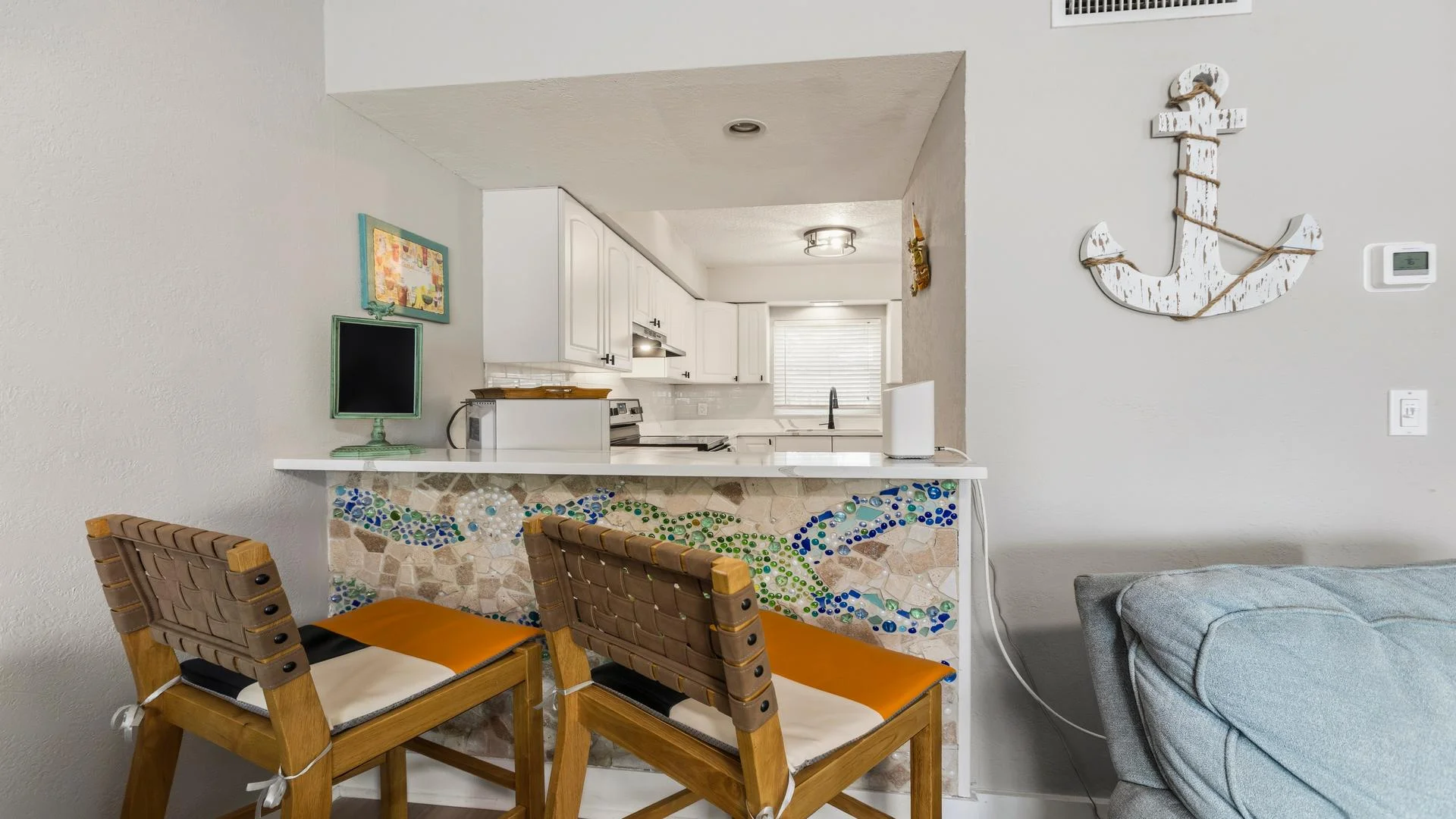 Kitchen pass-through bar decorated with mosaic tile and paired with woven leather strap wooden stools.