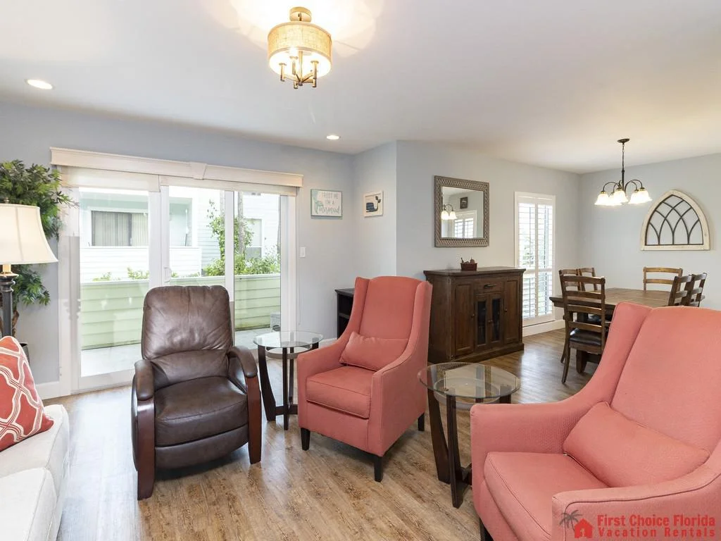 Two coral armchairs and a brown leather recliner frame glass-top side tables in the living room.
