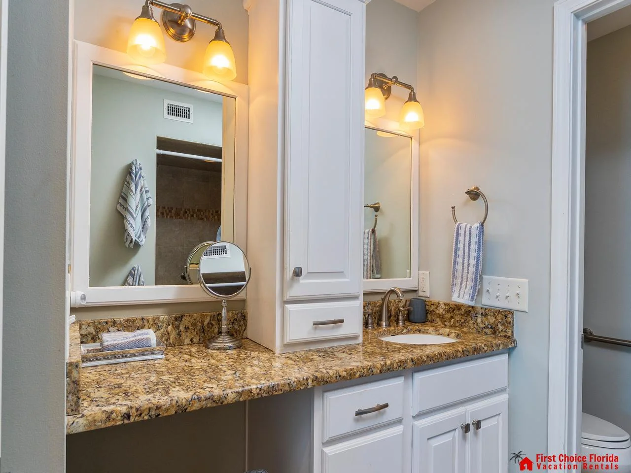 Bright, spacious primary bathroom with dual sinks and elegant granite countertops