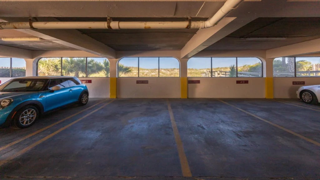 Covered parking space marked Unit #302 with concrete floor, arched windows, and yellow safety stripes.