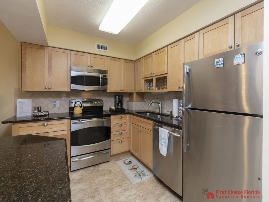 Under-cabinet lighting highlights the black granite countertops and tile backsplash in the kitchen.