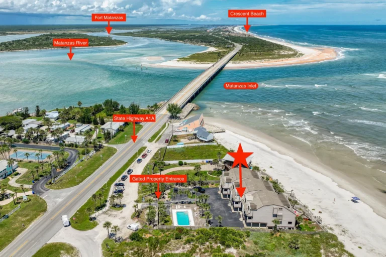 Cluster of beige beachfront condos with rooftop decks and direct stair access to the white sandy beach.