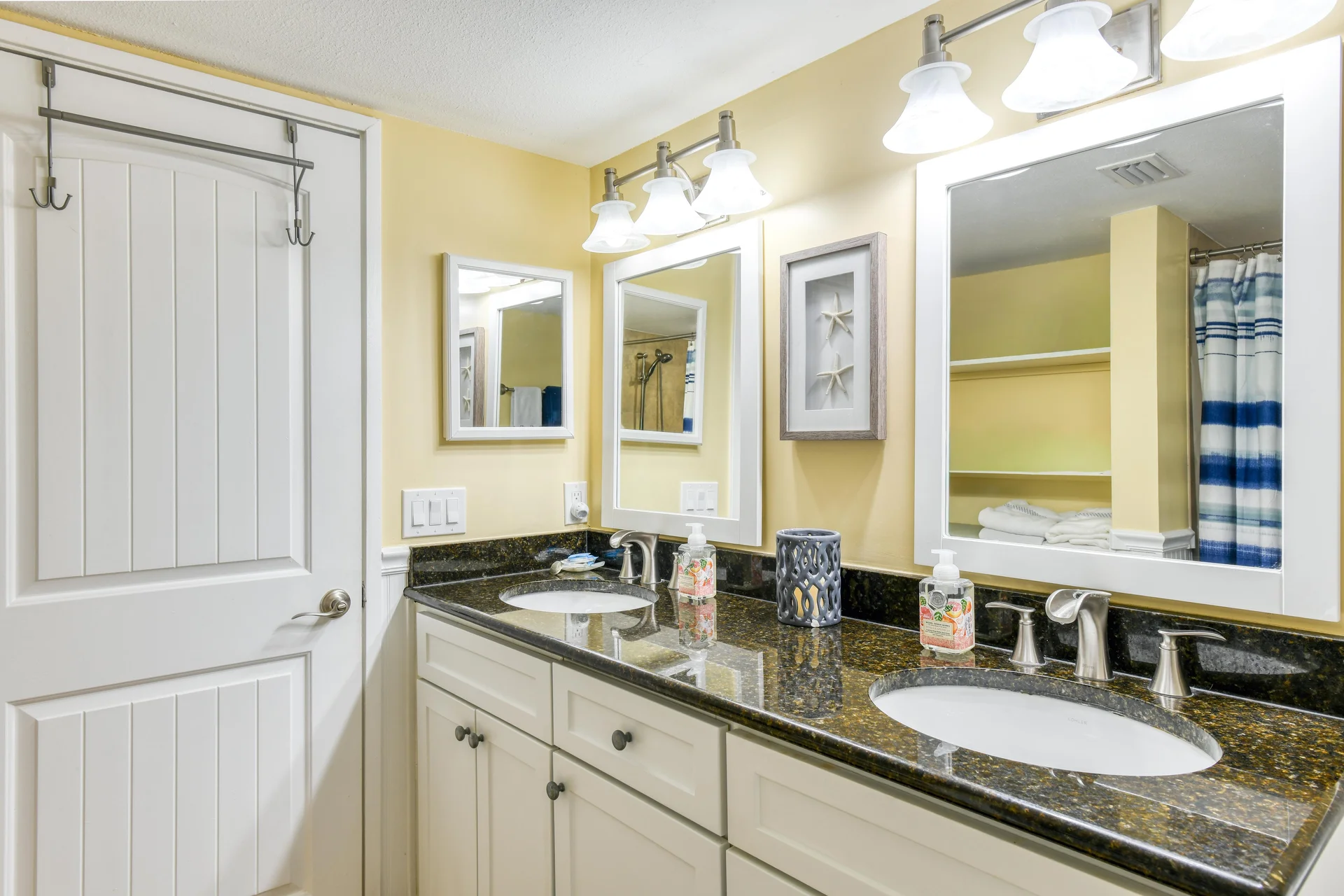 Double vanity bathroom with dark granite countertop, brushed nickel faucets, and framed white mirrors.