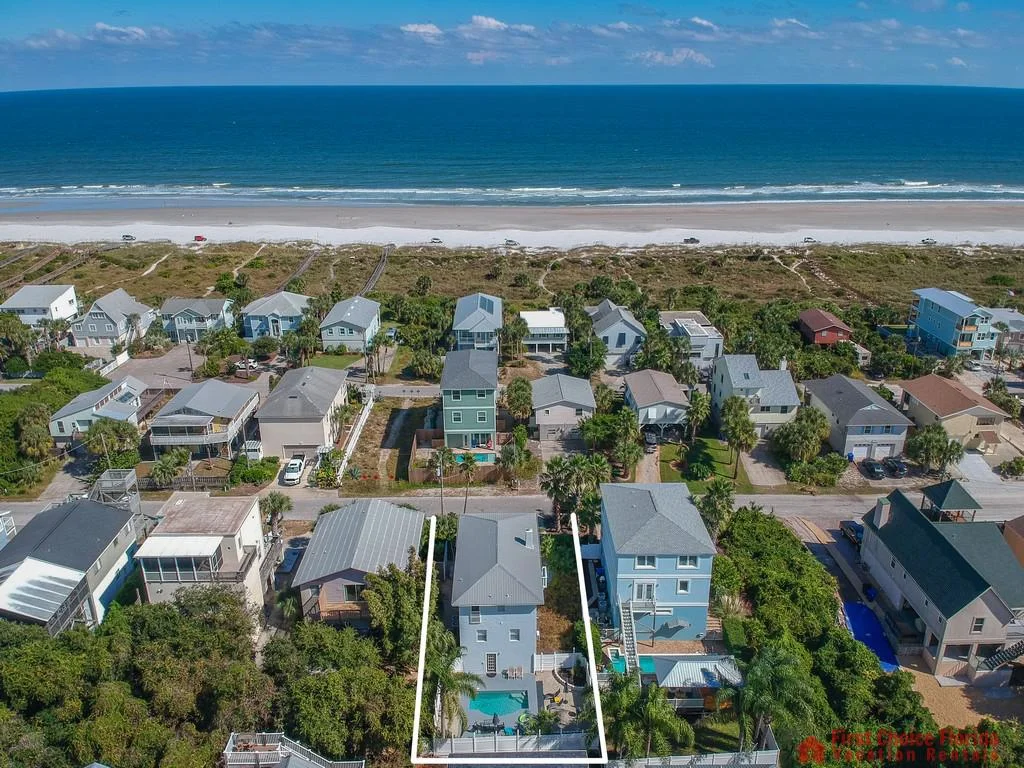Aerial view of the property outlined in white, showing the pool, surrounding houses, and ocean beyond the beach.
