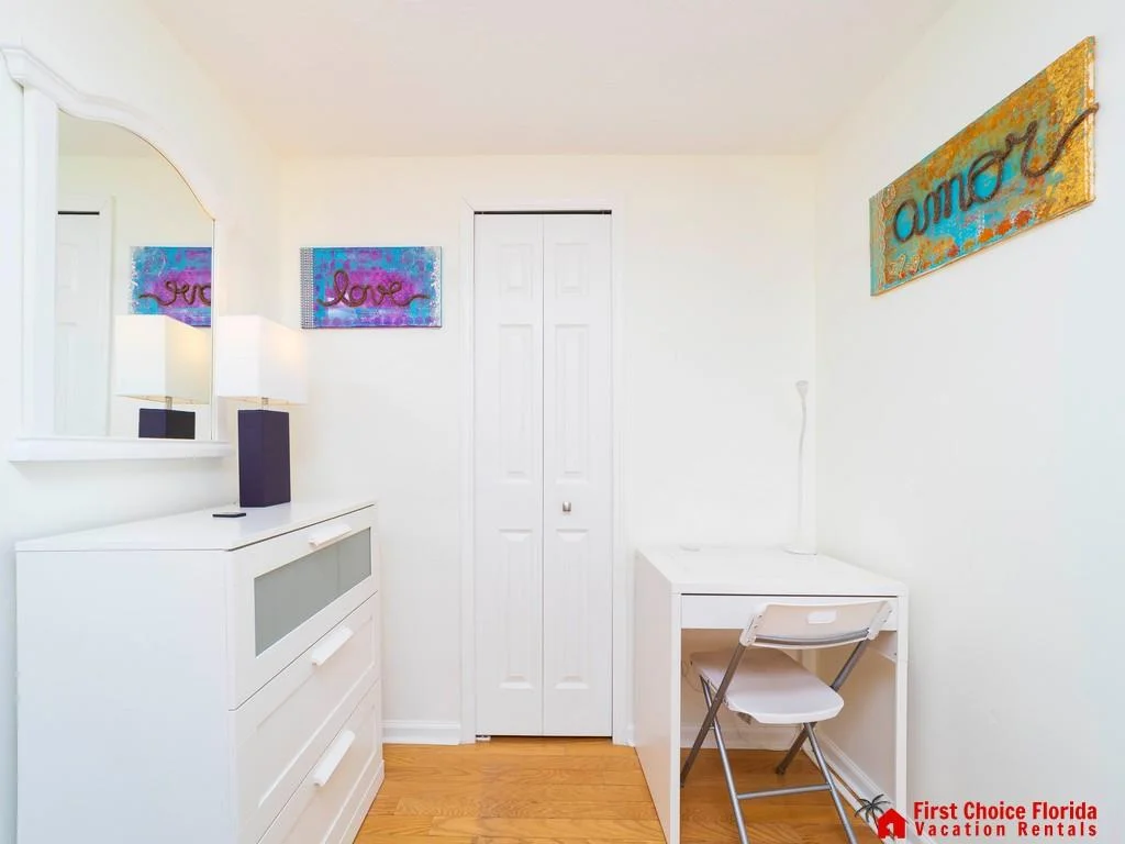 Bathroom wall with abstract blue and gold "amore" sign above a white desk and chair.