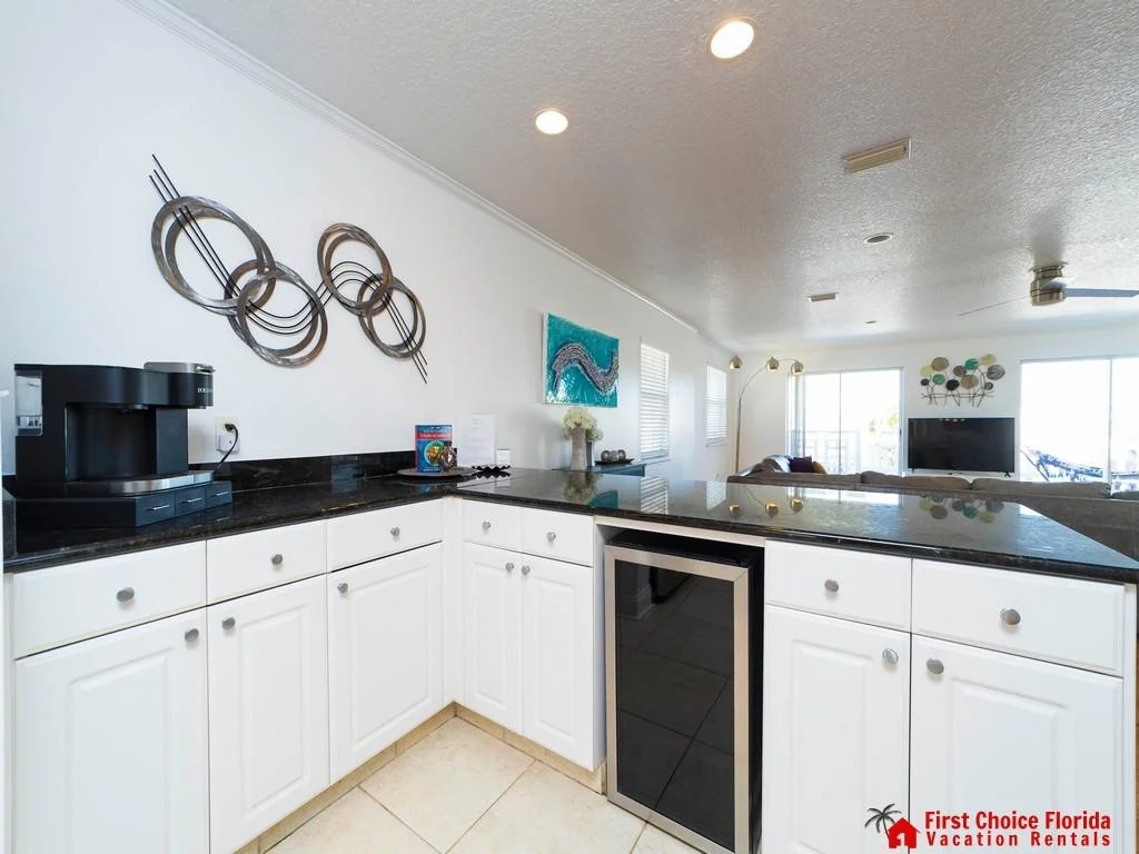 Black granite countertops contrast with white cabinetry and a built-in wine cooler in the kitchen.