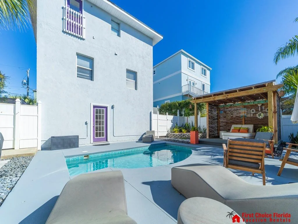 Pool area features a small rectangular pool with light blue tile trim, surrounded by gray concrete deck and cushioned loungers.