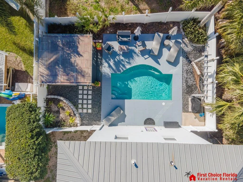 Private backyard pool area with blue water, gray concrete deck, lounge chairs, umbrellas, and a shaded pergola.