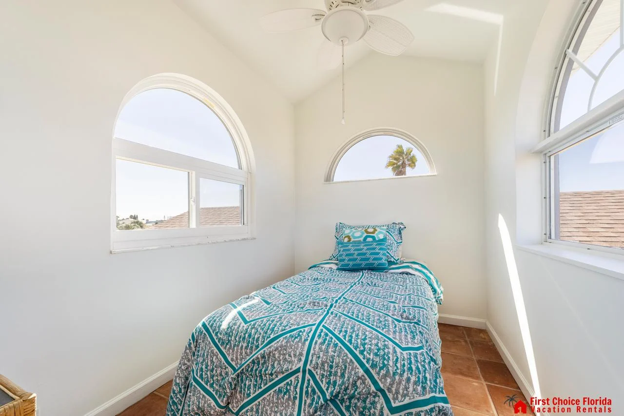 Cozy sunlit third floor bedroom with charming arched windows and vibrant bedding!