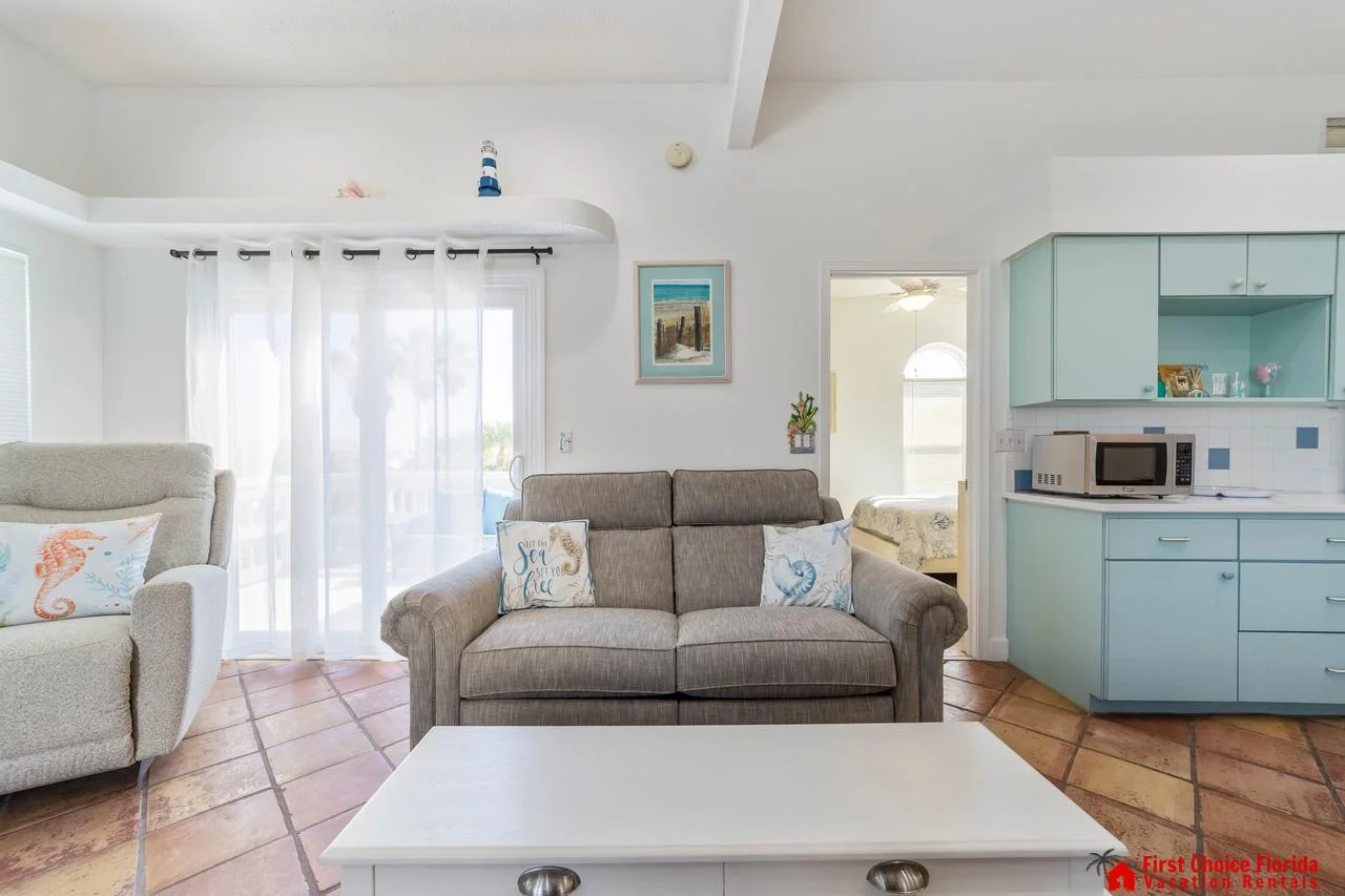 Cozy living room with bright natural light and pastel kitchen!