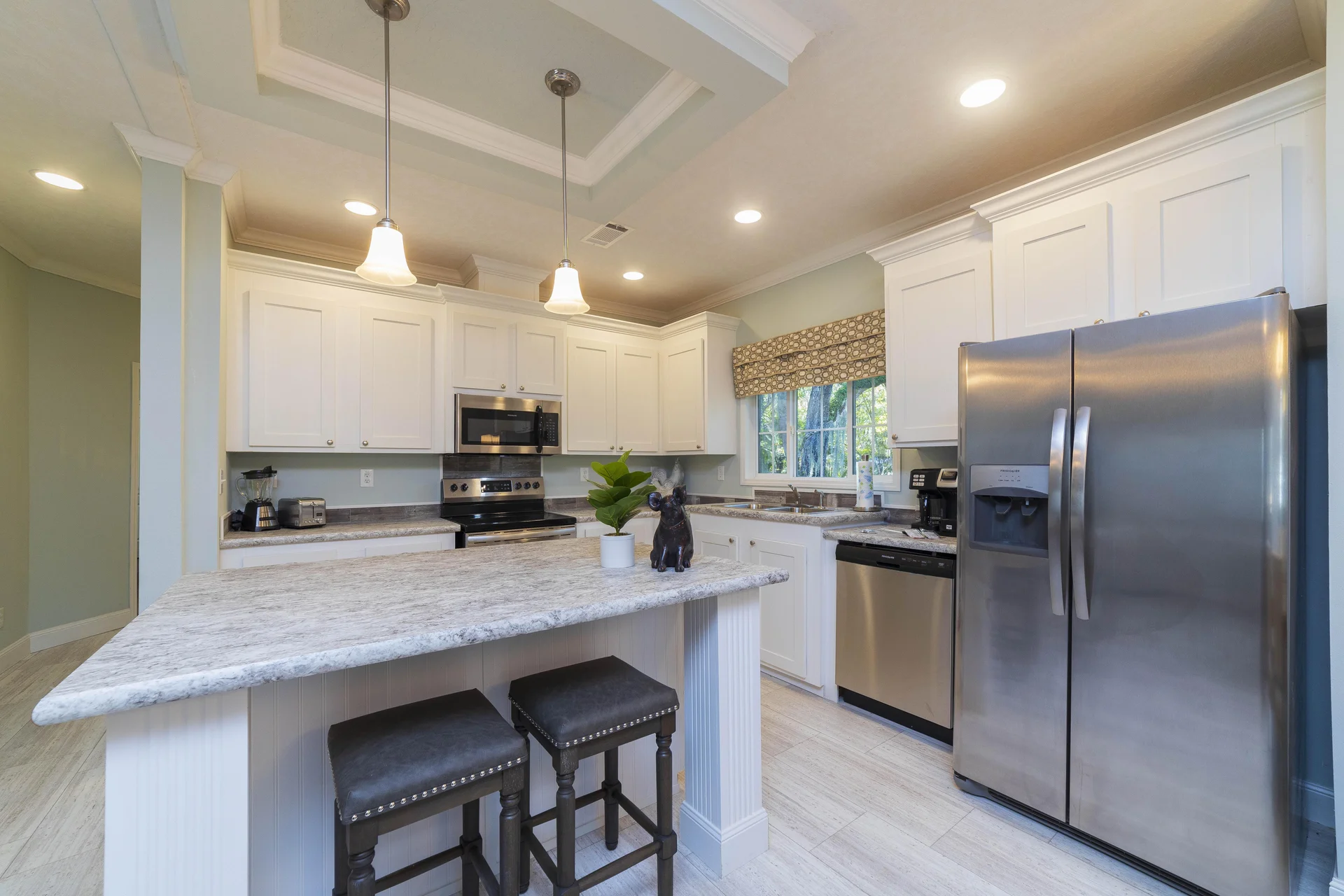 Kitchen with granite countertops, white cabinetry, stainless steel appliances, and two dark cushioned bar stools.