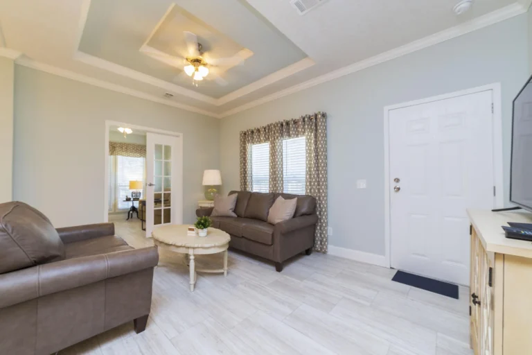 Entryway living area with light wood-look tile flooring, a tray ceiling, and patterned curtains over two windows.
