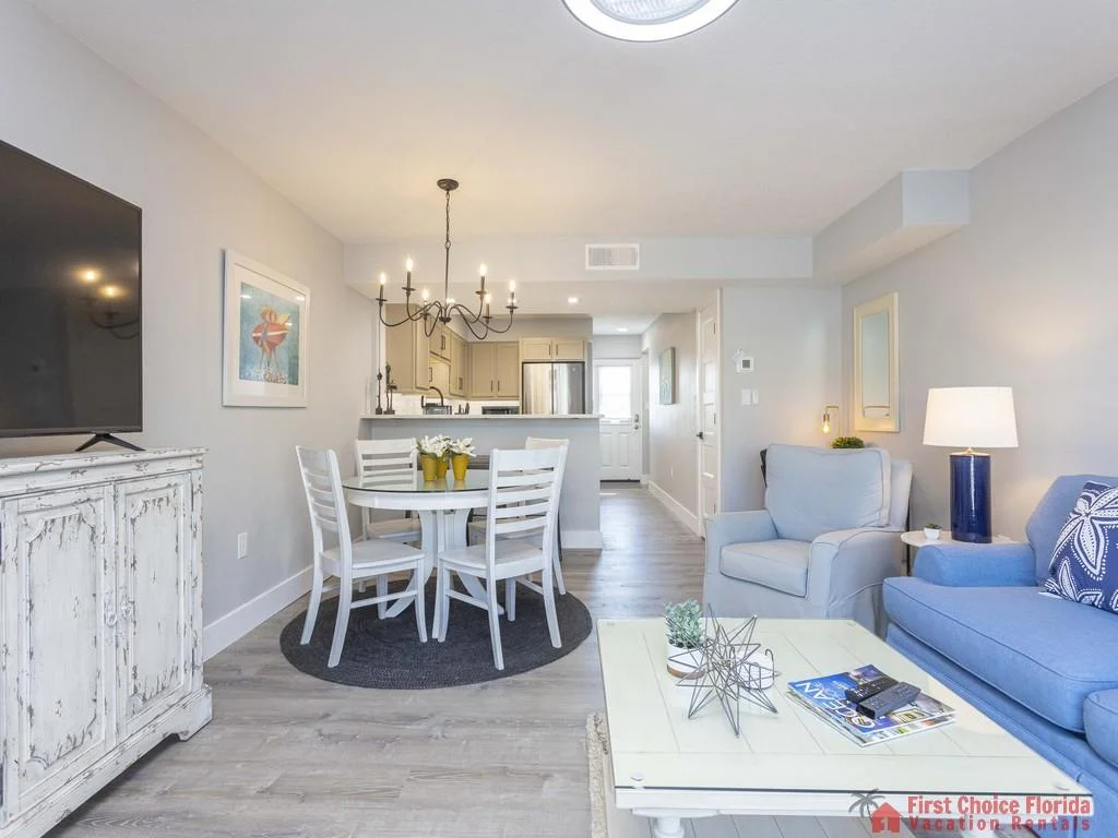 Whitewashed wood TV cabinet anchors the living area with a blue sofa, armchair, and glass-top coffee table.