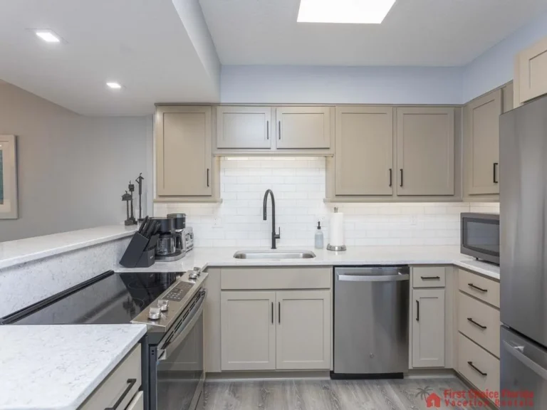 Matte taupe cabinetry contrasts with white subway tile backsplash and stainless steel appliances.