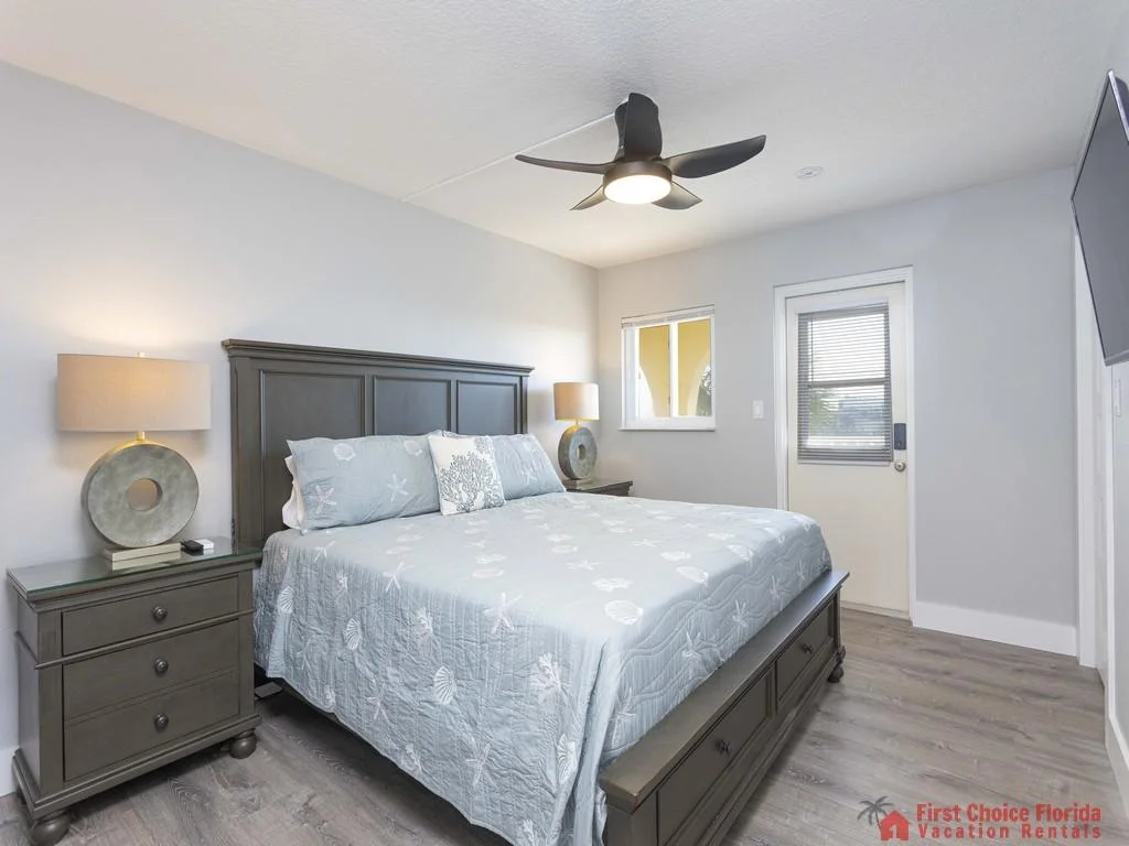 Two dark wood nightstands with circular table lamps flank a king bed under a black ceiling fan with integrated light.