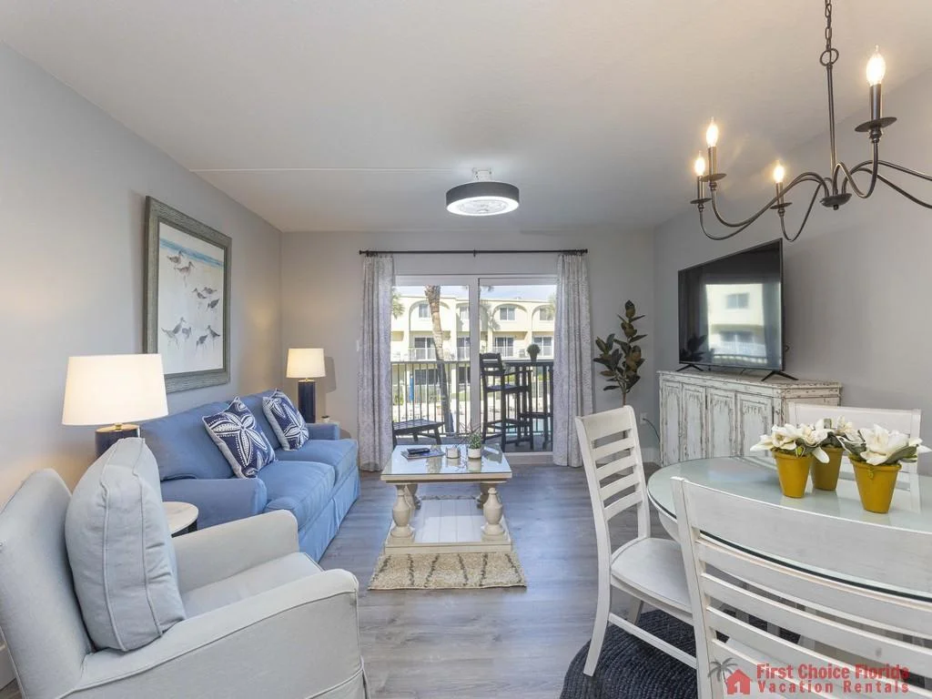 Light gray armchair and blue sofa with starfish pillows face a glass-top coffee table in the living room.