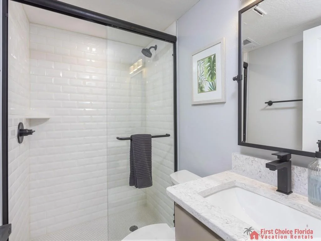 Bathroom features a white subway tile shower with glass door, black fixtures, and a light granite countertop.