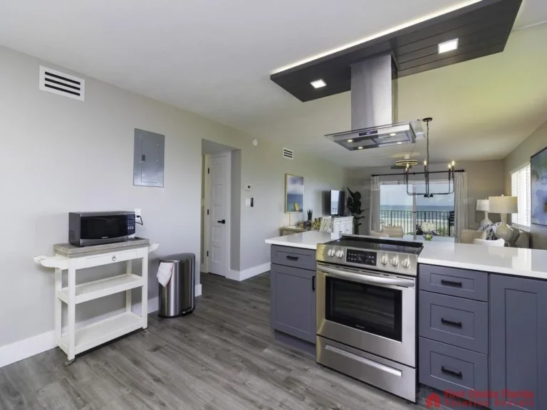 Blue shaker cabinets and white quartz countertops frame the stainless steel range beneath a modern vent hood in the kitchen.
