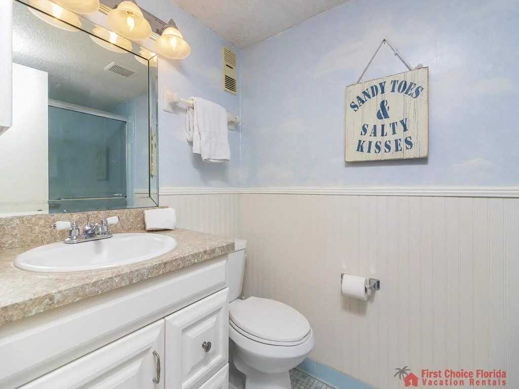 Bathroom with a beige granite countertop, white cabinetry, and a glass-enclosed shower behind a sliding door.
