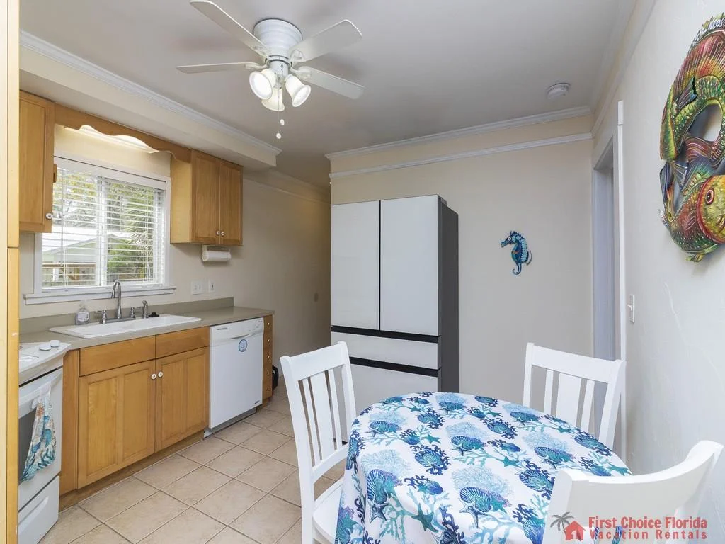 Two white beds with blue patterned bedding sit beneath a white ceiling fan and wall-mounted seahorse decor.