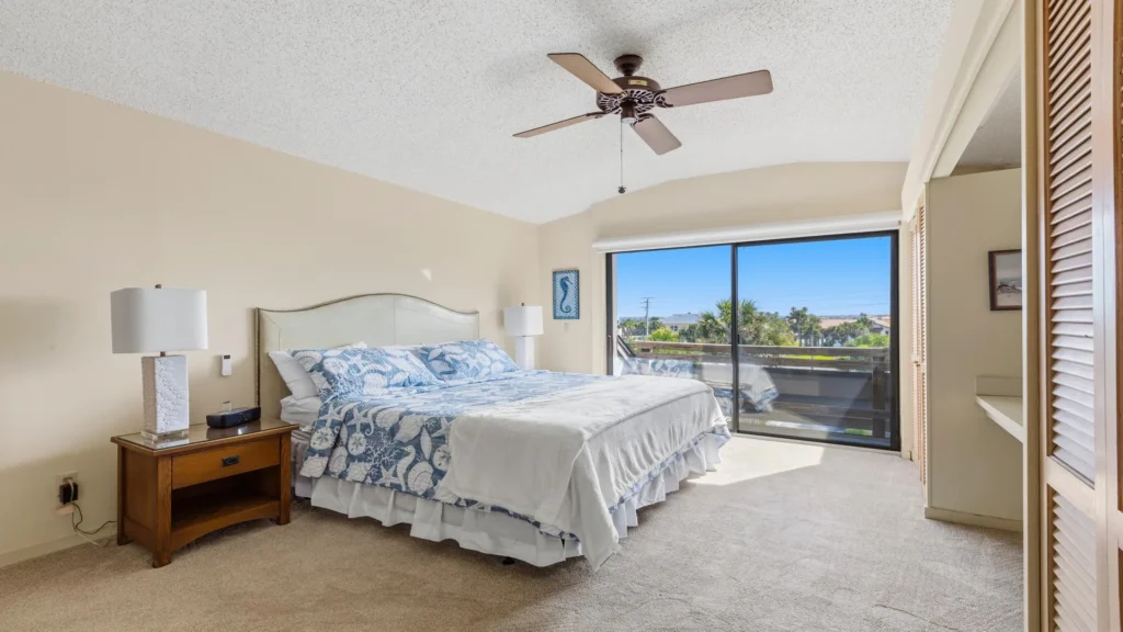 Sliding glass doors open to a balcony with ocean views, filling the bedroom with natural light.