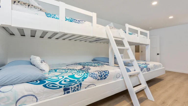 White wooden bunk bed with ladder, decorated in blue and white sea turtle patterned bedding.