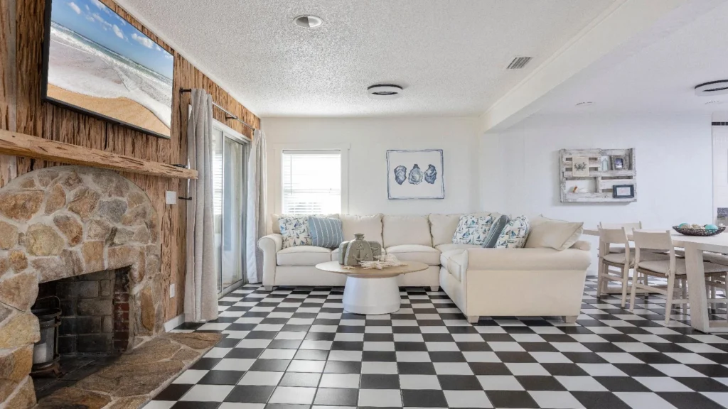 Black-and-white checkered tile floor extends through living and dining areas with stone fireplace and light wood furniture.