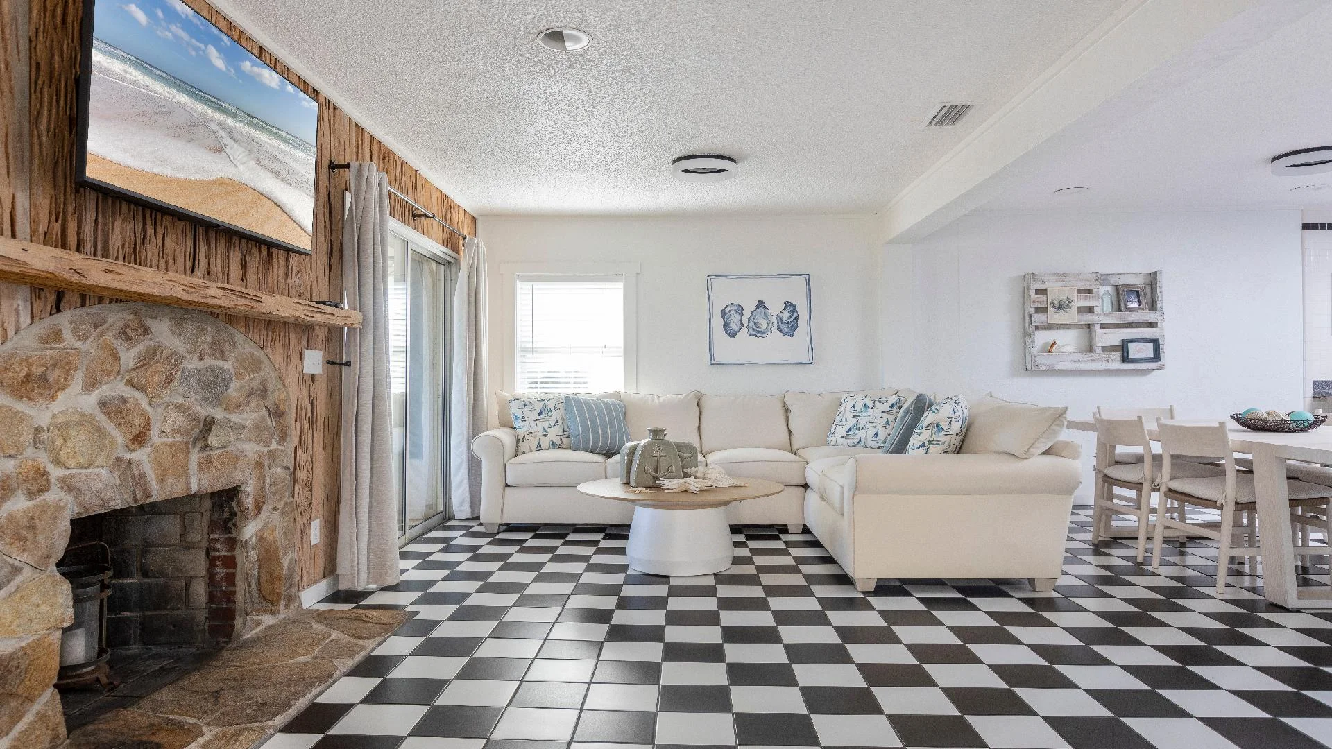 Black-and-white checkered tile floor extends through living and dining areas with stone fireplace and light wood furniture.